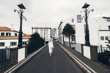 Fototapeta na wymiar Woman traveling in Azores island walking in city with white buildings