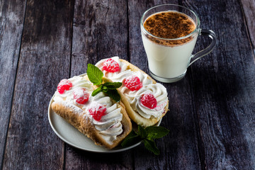 Air cake with raspberries on a saucer. Kefir with cinnamon, fermented drink. wood background