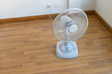 Table electric fan sit on the wooden floor
