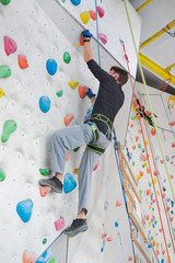 Obraz premium Mężczyzna wspina się na ścianę wspinaczkową.
