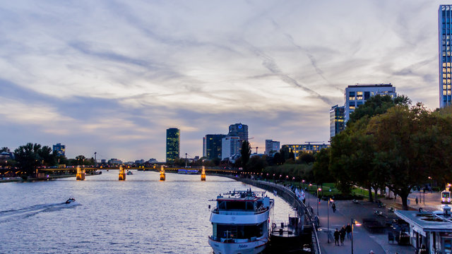 varco a la orilla de un rio con u puente al fondo a la puesta de sol