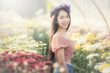 Beautiful young woman traveler looking flowers field sitting on a blurred flowers garden background. Travel holiday relaxation concept. .