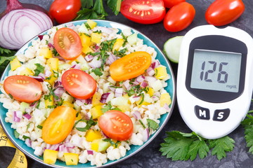 Glucometer with sugar level, salad with vegetables and bulgur groats, tape measure. Diabetes and healthy meal containing natural vitamins