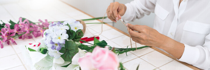 young women business owner florist making or Arranging Artificial flowers vest in her shop, craft and hand made concept