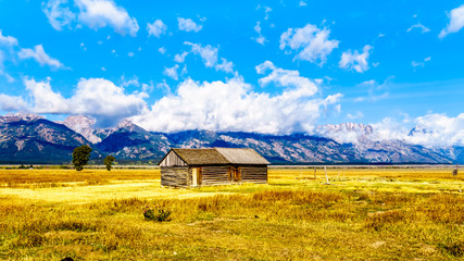 Obraz premium An abandoned Barn at Mormon Row with in the background cloud covered Peaks of the Grand Tetons In Grand Tetons National Park near Jackson Hole, Wyoming, United States