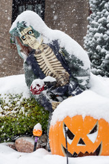 Halloween skeleton decoration in a front yard during a snowstorm.