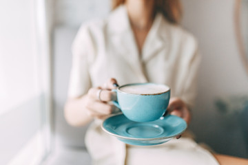  atmospheric coffee shop and stylish dishes. hot mug of coffee in the hands of a young girl.