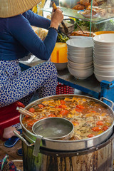 Woman cooking Bun Rieu, Vietnamese popular noodle soup at vendor