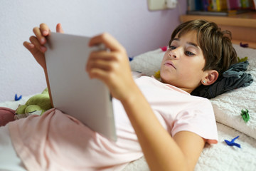 Obraz na płótnie Canvas Cute girl using a tablet computer in her bedroom