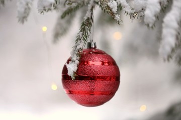 Christmas and New Year  festive background.Red Christmas ball and shining garland on a spruce snow branch on a blurred winter snow forest background.IPhone Wallpaper. Winter festive decor