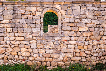part of an old stone wall with an arched window opening in the archaeological museum of Chersonesos