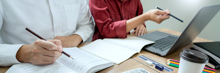 Teaching helping technology concept. Woman young teacher or tutor with adult students in classroom at desk with papers, laptop computer. Studies course