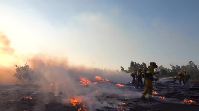 2019 - ground fire burns as firefighters battle a burning structure during the Easy Fire wildfire disaster in the hills near Simi Valley Southern California.