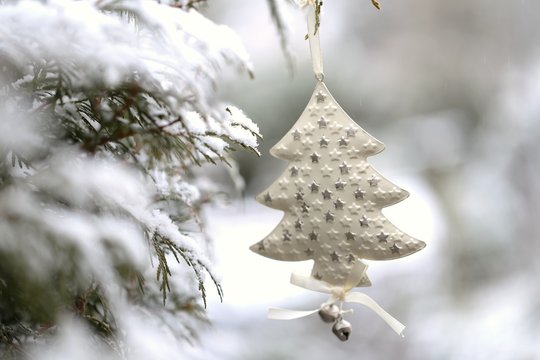 Christmas and New Year  festive background.White Christmas decorative tree on a snow thuja branch on a blurred winter snow garden background.