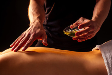 close-up masseur hands doing back massage to female client in spa center panchakarma