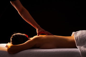 Masseur hands doing back massage to client in spa center in dark room