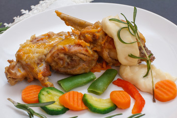 Rabbit legs baked in white wine with bechamel sauce on a ceramic plate.