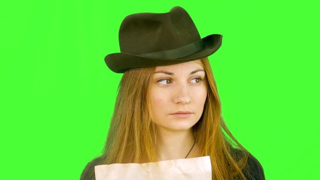 the girl in the hat looks at the old map and looks around, closeup green screen background