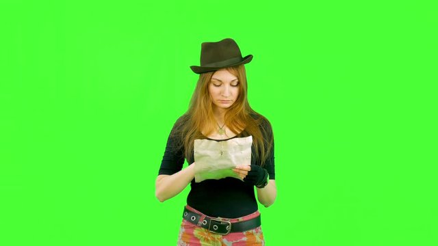 young girl in a hat studies an old map of her tourist route green screen