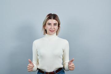 Attractive caucasian woman in wearing nice pastel clothes, keeping thunbs up, smiling to present a...