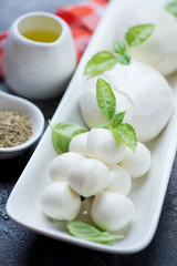 Close-up of mozzarella cheese with olive oil and green basil leaves, vertical shot, selective focus