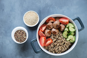 Food bowl with roasted meatballs, quinoa and vegetables over grey concrete background, flatlay, horizontal shot