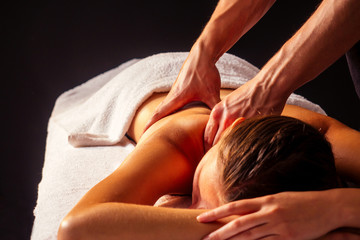 close-up masseur hands doing back massage to female client in spa center