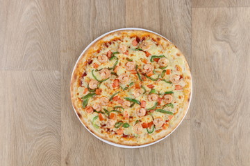 shrimp pizza with vegetables on a wooden background