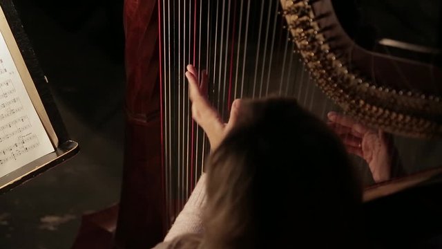 Close-up shot of hands playing the harp at the rehearsal of the Symphony orchestra
