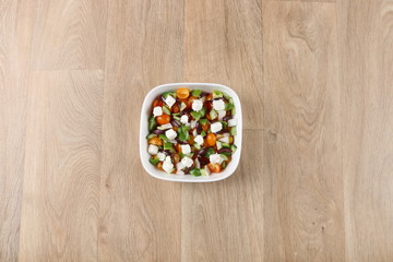 Mediterranean salad with fresh vegetables in a withe bowel  on a wooden background