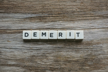 Demerit in alphabet on wooden background. 