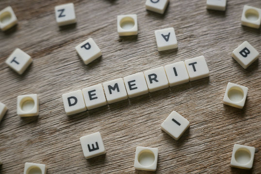 Demerit in alphabet on wooden background. 