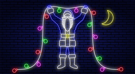 Neon christmas sign. Santa Claus in blue clothes. Holds the new year glowing colorful illumination, with his hands up. Against the background of a brick wall. Near the moon.