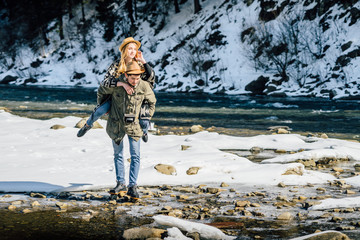 Winter couple piggyback in snow mountains smiling happy and excited. Beautiful young couple