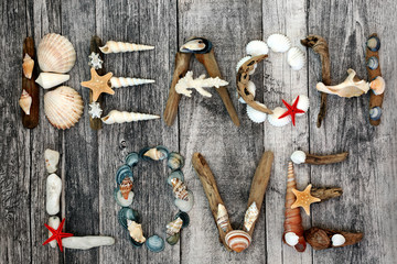 Abstract of driftwood, seashells and pebbles forming the word beach love on rustic wood background. Summer holiday theme. Flat lay.