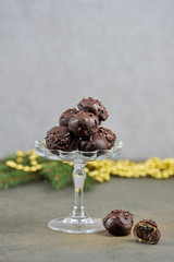 Handmade chocolates in a glass vase. On the surface of the table are some sweets. The vertical orientation of the frame. Gray background.