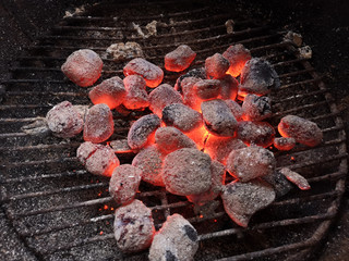 close up glowing charcoal briquettes on grill grate