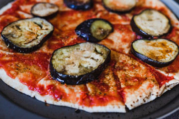 pizza base with tomato sauce and aubergine before going in the oven