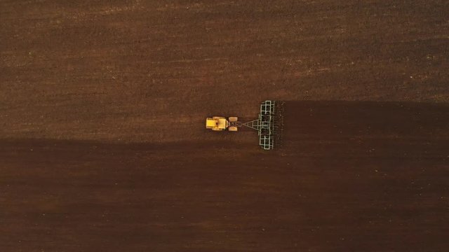 Aerial view of a powerful yellow tractor with great effort on the hook performing plowing tillage for sowing winter crops with a disk cultivator in the fall