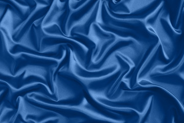 Close up of ripples in blue silk fabric. Satin textile background.