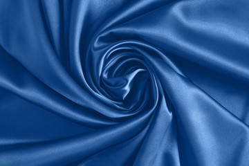 Fototapeta na wymiar Close up of ripplesin shape of rose flower in blue silk fabric. Satin textile background.