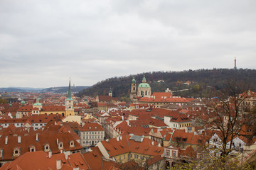 Obraz premium Panorama of the Czech city of Prague with tiled orange roofs from the observation deck of Prague Castle on a cloudy day on the eve of Christmas.