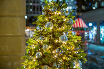 Colorful golden glass baubles and bokeh on a Christmas tree in Zurich  with a merry-go-round in the background - 1