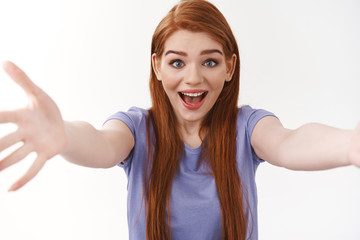 Naklejka na ściany i meble Cheerful friendly-looking tender redhead woman with long ginger hair, stretch hands forward to hold or catch something, smiling amused, embracing friend, meet sibling and hugging them