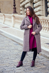 Young stylish woman buttoning coat buttons walking on the street in Czech Republic Prague sity
