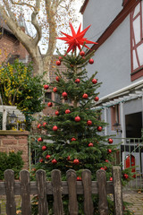 Fototapeta na wymiar Christmas tree decorated with red balls and a chain of lights outdoors in an old town alley in Aschaffenburg, Bavaria, Germany