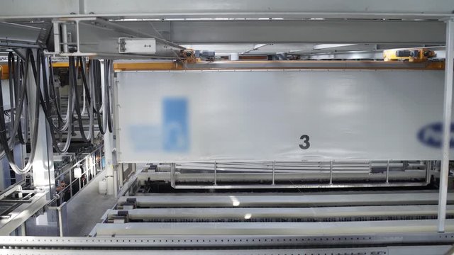 Aluminum profiles are immersed in a special solution with help girder crane. The anodizing. The process of anodizing of aluminum in the enterprise. Metal processing.