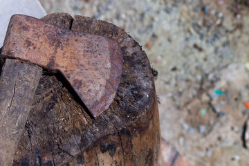 Close-up on a rusty ax above a wood stump