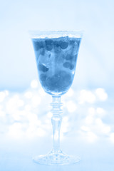 Glass of champagne and cranberry cocktail, macro. Lightweight background. Christmas mood. Vintage style. Vertical, toned in blue.