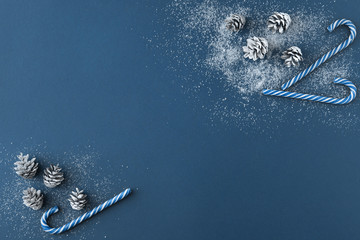 Top view of Christmas composition of snowy fir tree cones, blue candy cane decorations on Classic...
